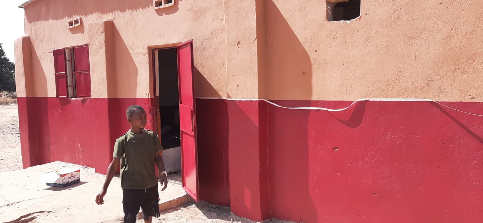 Blackhall Madrasa exterior after restoration — red painted door and repaired walls